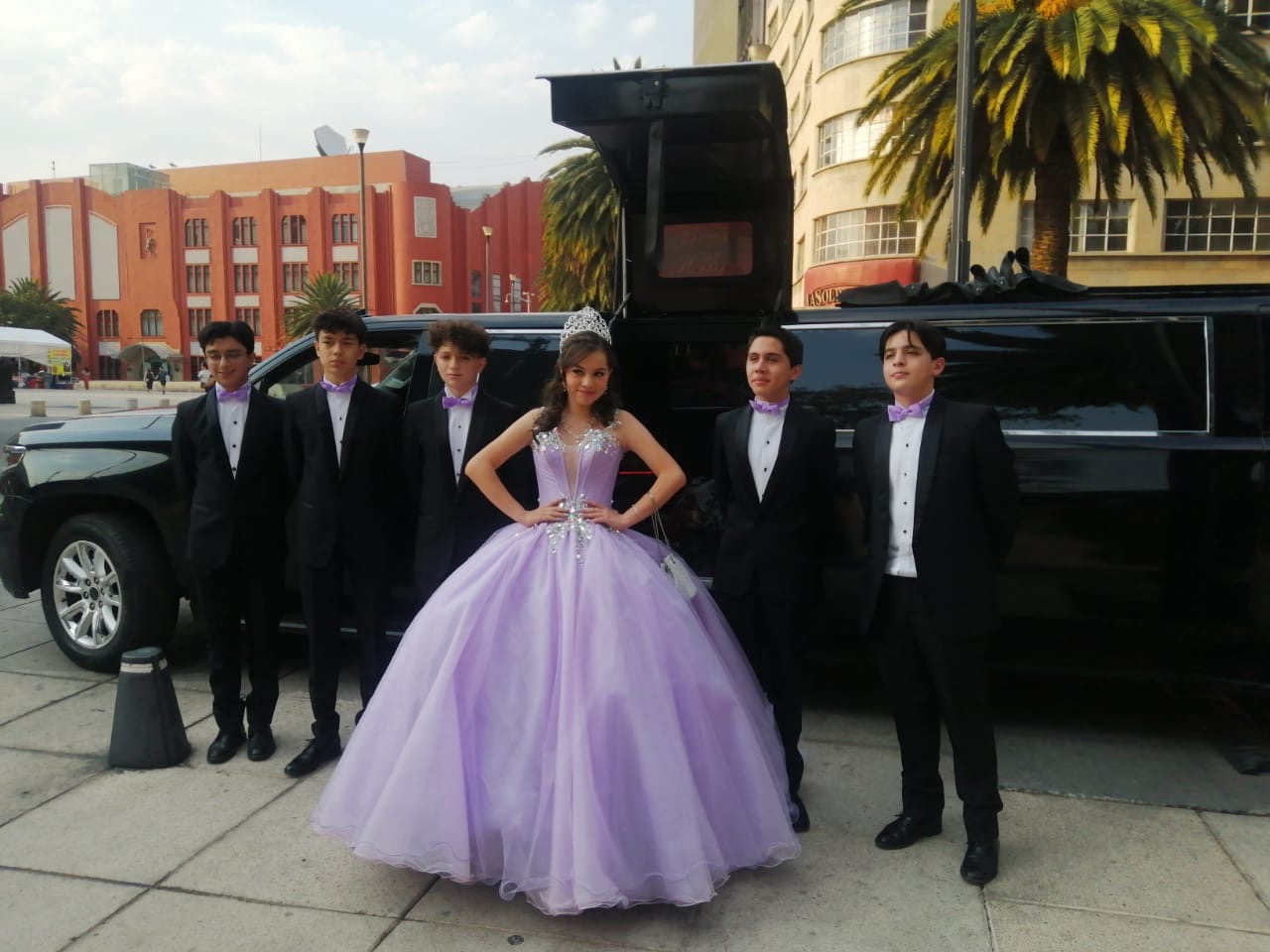Quinceañera lila con acompañantes frente a unidad negra